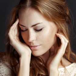 Beautiful woman with eyes closed and touching her face